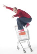 jeune homme surfant sur un caddie de commerce