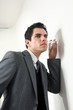 junger business mann hört an einer wand mit glas