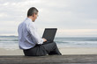 Geschäftsmann arbeitet mit Laptop am Strand