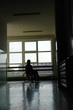 Silhouette of wheelchair woman looking through window
