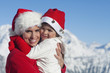 Mother and dauhter wearing Santa hats, hugging