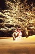 Young couple making heart shape with sparkler by night