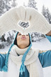 Young woman in winter clothes making heart shape with hands