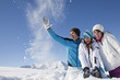 Couple and daughter in ski wear, throwing snow in air