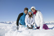 Couple and daughter sitting in snow, smiling at camera