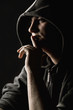 Hooded man holding a finger to his mouth Hooded man holding a finger to his mouth