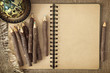 Open exercise book with pencils on brown background