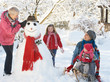 Young Girl With Grandmother And Mother Building Snowman In Garde