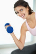 Biceps - Young happy female working out with a dumbbell