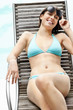 Summer vacation - Young female relaxing on a recliner by pool