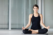Cute young female practicing yoga on a mat in the lotus pose