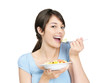 Young female eating a bowl of fresh fruits against white