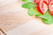Wooden cutting board, sliced tomatoes and lettuce in corner.