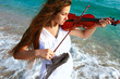 Photo: young attractive woman playing violin on sea background young attractive woman playing violin on sea background