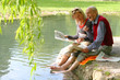 Großvater und Enkelin beim Zeitunglesen im Grünen am Teich Großvater und Enkelin beim Zeitunglesen im Grünen am Teich