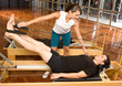 Girl assisting man during pilates