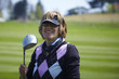 portrait of a golfer woman holding iron and smiling.