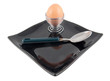 boiled egg and spoon on black plate on white background
