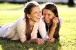 Young beautiful twins of sister lays on green field