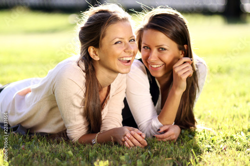 Foto: Young beautiful twins of sister lays on green field Young beautiful twins of sister lays on green field