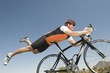 Male cyclist balances his stomach on bicycle seat