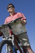 Mature man stands looking at map with mountain bike