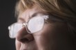 Mature woman with light reflecting on reading glasses