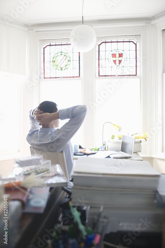 Photo: Businessman works from desk in bay window Businessman works from desk in bay window