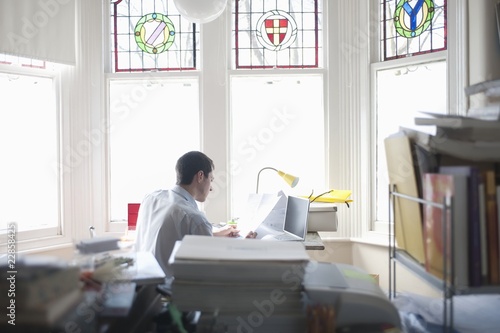 Photo: Businessman works from desk in bay window Businessman works from desk in bay window
