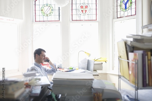 Photo: Businessman works from desk in bay window Businessman works from desk in bay window