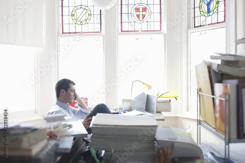 Photo: Businessman works from desk in bay window Businessman works from desk in bay window