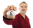 Man holds an egg with British pound currency symbol on it. Man holds an egg with British pound currency symbol on it.