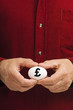 Man holds white egg with the British pound symbol (£) written on Man holds white egg with the British pound symbol (£) written on