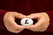 Man holds white egg with the British pound symbol (£) written on Man holds white egg with the British pound symbol (£) written on