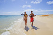 beachboy plays his ukulele for a girl as they walk on a beach