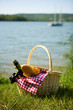 Picnic basket with food and cider bottle near the water