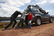 Family pushing broken car