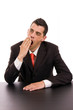 yawning young business man on the desk, isolated on white backgr