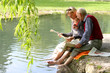 Großvater und Enkelin beim Zeitunglesen im Grünen am Teich Großvater und Enkelin beim Zeitunglesen im Grünen am Teich
