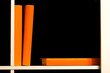Three orange covered books on a white shelf over dark