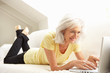 Senior Woman Using Laptop Relaxing Sitting On Sofa At Home