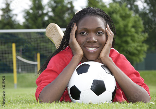 Photo: Junge Afrikanerin mit Fussball vor dem Tor liegend Junge Afrikanerin mit Fussball vor dem Tor liegend
