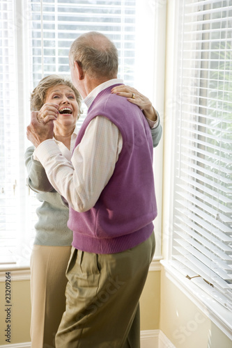 Photo: Loving senior couple dancing in living room Loving senior couple dancing in living room