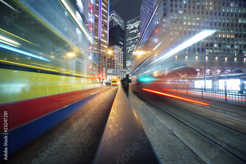 Fast moving bus lights blurred over modern city background