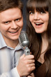 young beautiful woman and smiling man sing in microphone young beautiful woman and smiling man sing in microphone