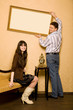 woman sitting on sofa in room and smiling man hang picture