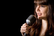young beautiful woman sing in microphone isolated on black young beautiful woman sing in microphone isolated on black