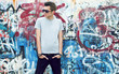 Photo: young man posing in front of a colorful graffiti wall young man posing in front of a colorful graffiti wall