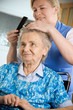 Nurse dressing the hair of a senior woman