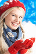 Young Woman Wearing Warm Winter Clothes And Hat Holding Snow In